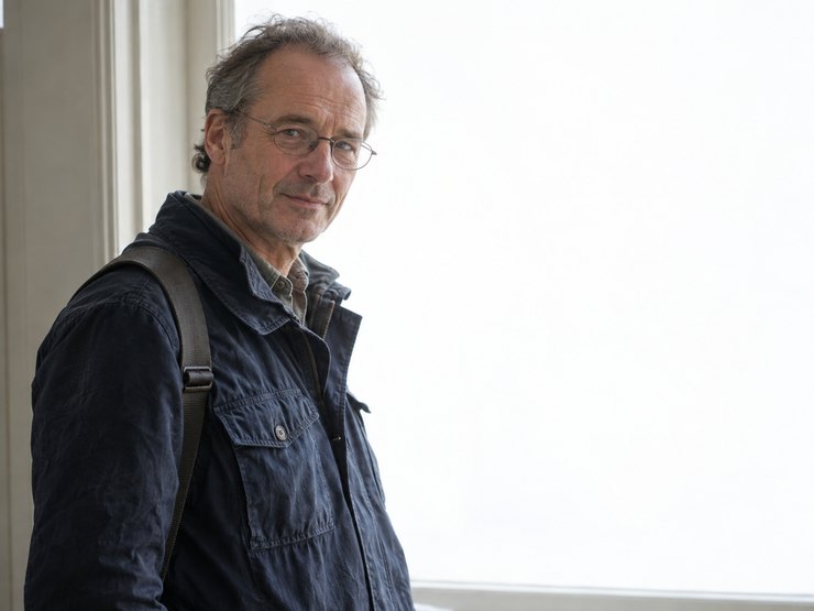 Ivan Petrov photographed against a bright window with a camera strap over one shoulder