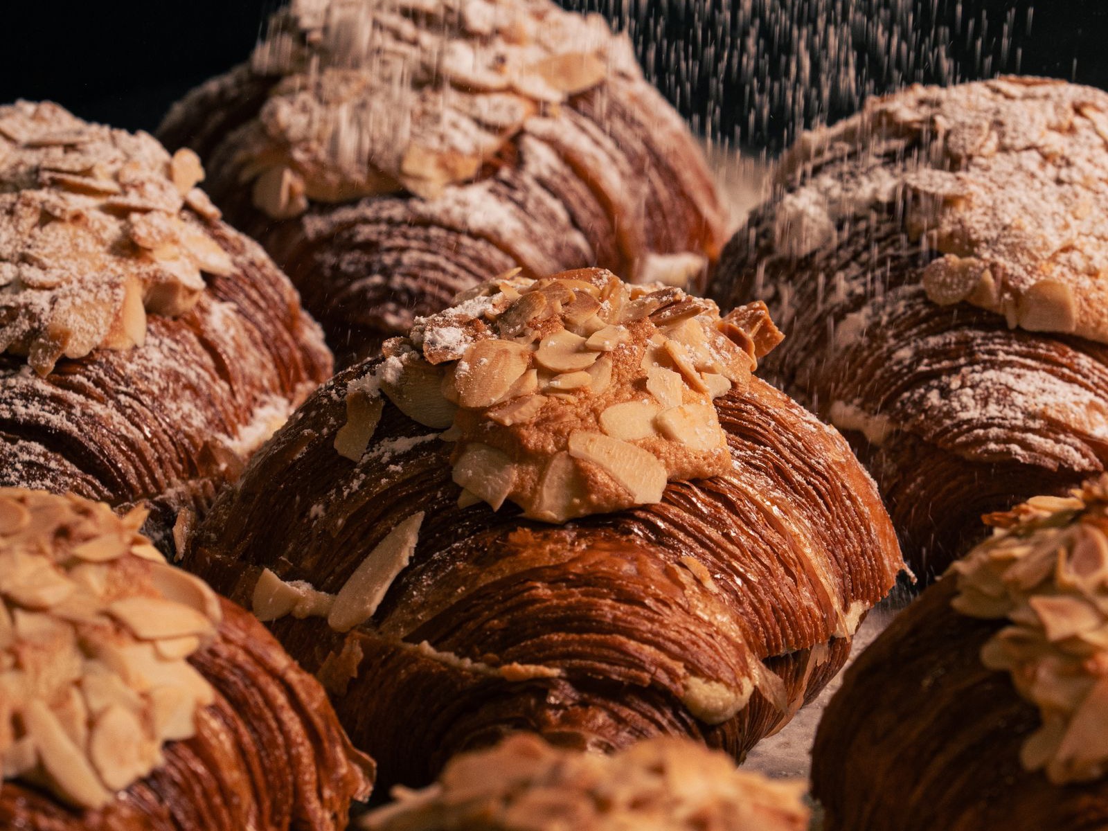 Almond croissants topped with flaked almonds and dusted with icing sugar