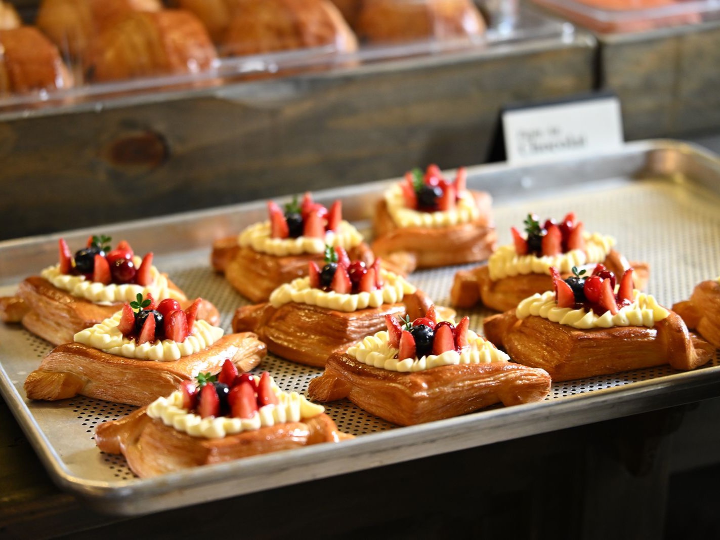 A tray of danish pastries topped with cream and fresh berries