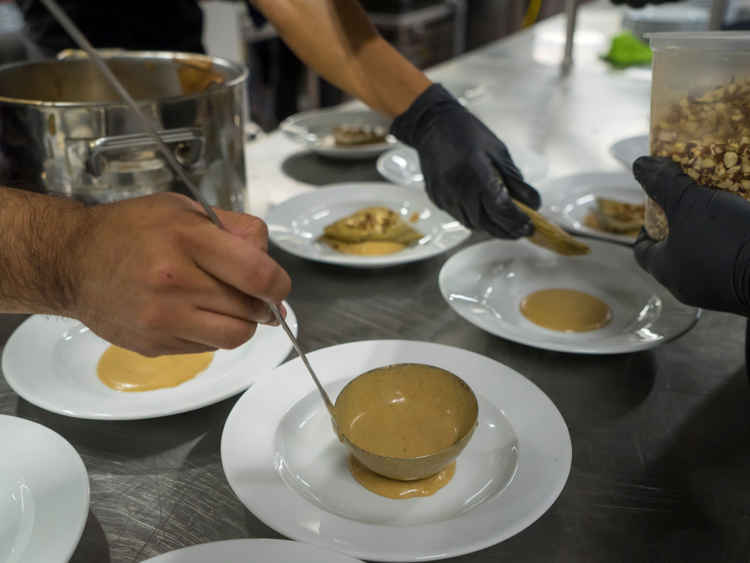 Chefs plating dishes side by side in a restaurant kitchen