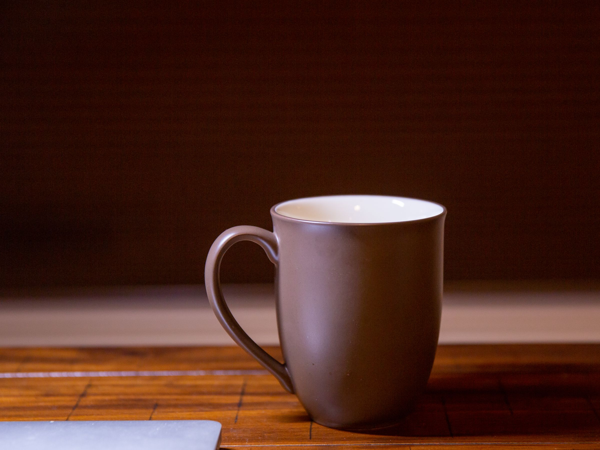 A plain brown stoneware mug on a wooden table