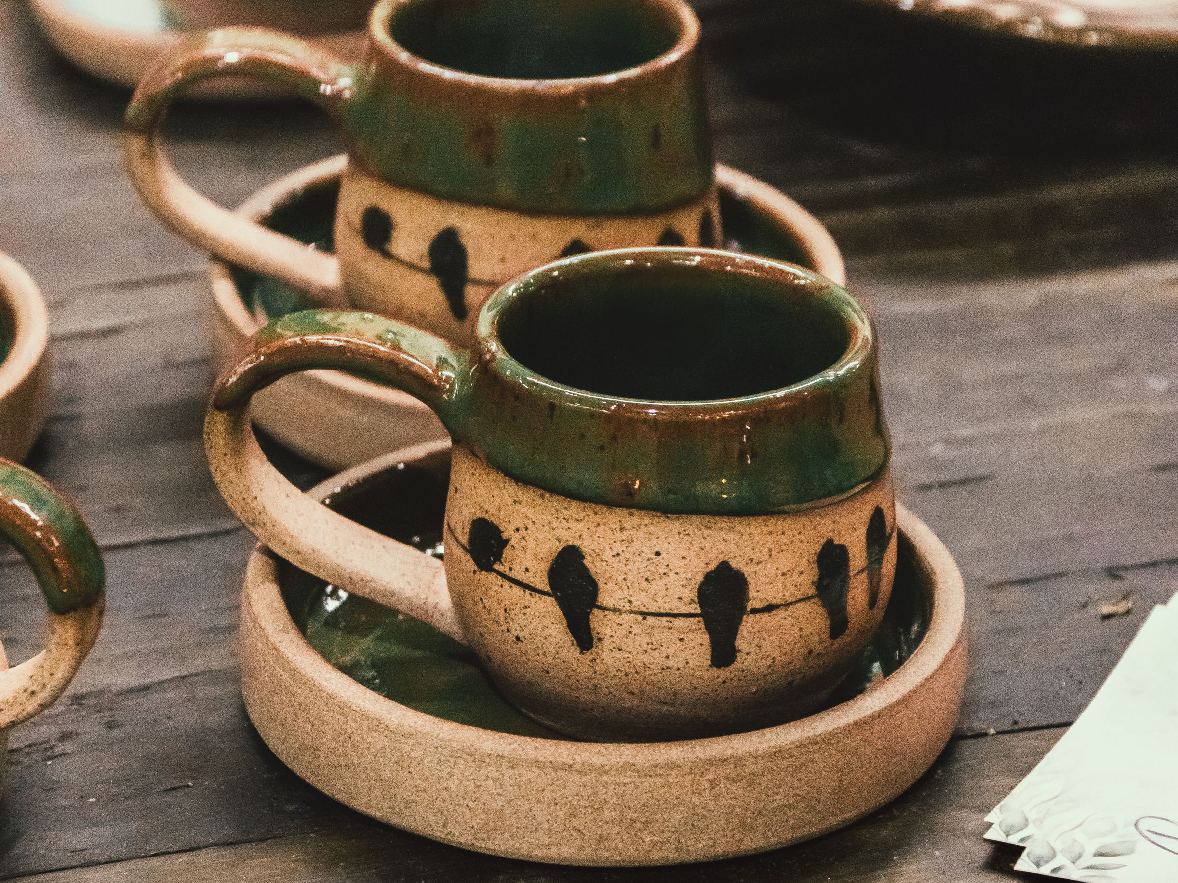 Two artisan ceramic cups with an earthy glaze on a wooden table