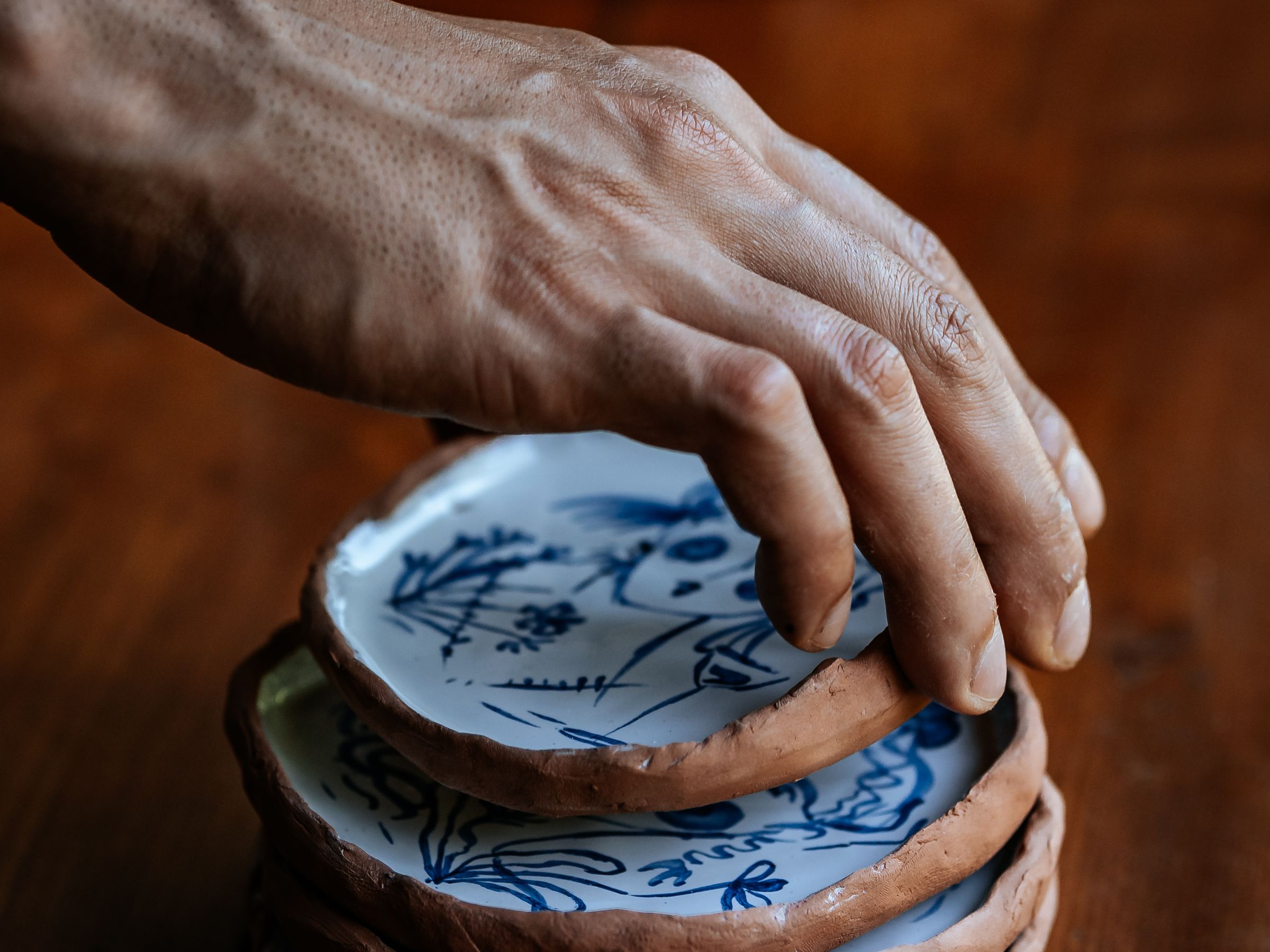 Handmade ceramic plates being stacked on a wooden table