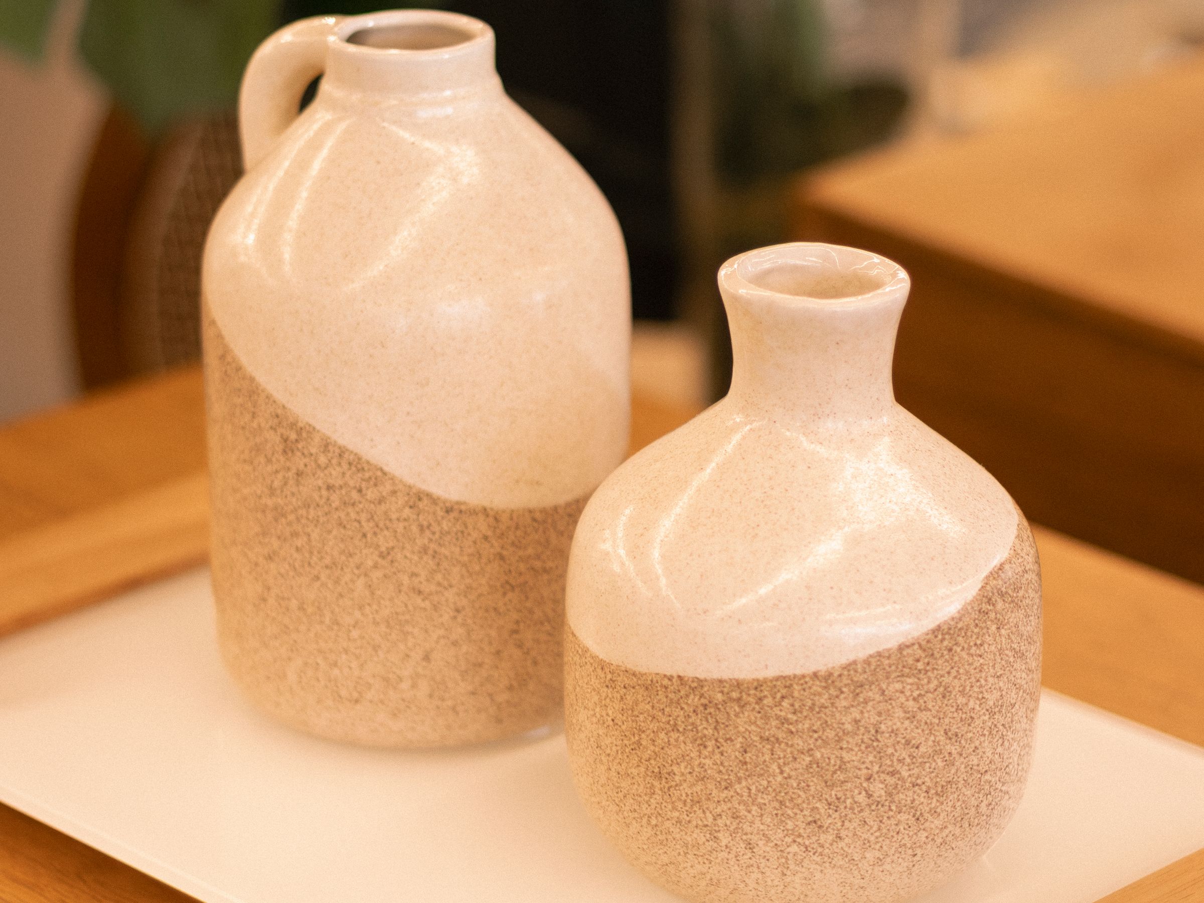 Two minimal ceramic vases standing on a wooden tray