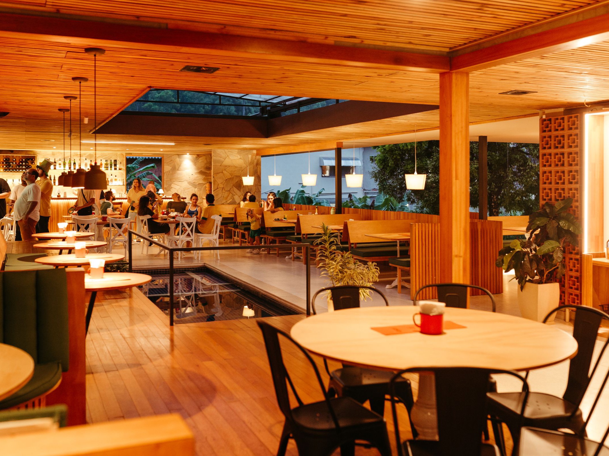 A dining room at night, twelve seats, candles and dark green walls, a waiter in motion, blurred